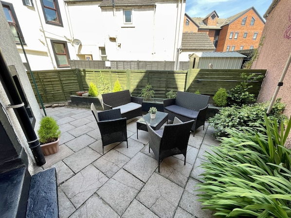 A patio with outdoor furniture, a small table, and potted plants. - The Oaks Cottage (Penrith)
