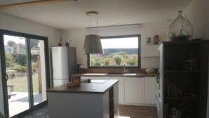 Eine kompakte Küche mit einer zentralen Kochinsel, einer integrierten Spüle und einem Fenster mit Blick auf den Garten.