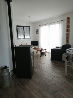 Ein Wohnzimmer mit einem schwarzen Herd, einem Holztisch, einer schwarzen Couch und einem Fernseher.