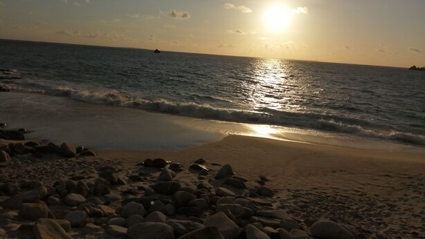 Ein Strand mit Felsen im Vordergrund und dem Meer im Hintergrund.