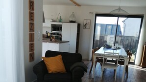 Ein Wohnzimmer mit einer Couch, einem Holztisch und einem Essbereich mit Tisch und Stühlen.