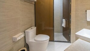 A modern bathroom with a toilet, shower, and sink.
