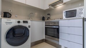 Una cocina compacta equipada con lavadora, horno, microondas y cafetera.