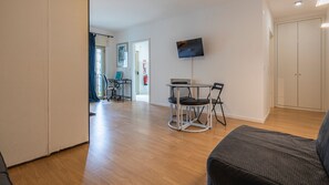 Un salon moderne avec une table ronde, deux chaises, un téléviseur à écran plat et un canapé.