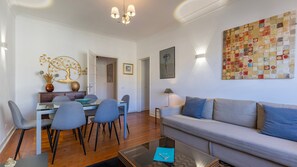 A modern living room with a sofa, dining table, chairs, and a coffee table.