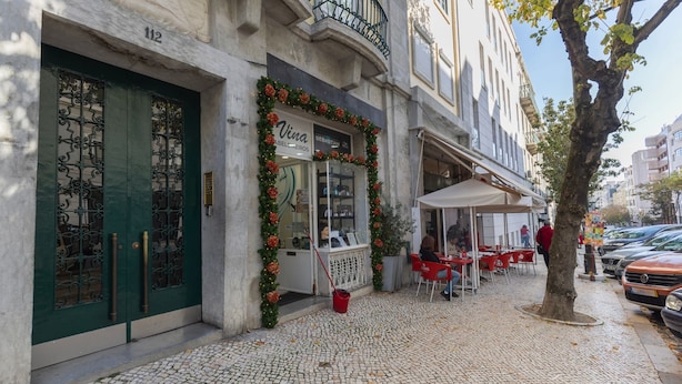 Una calle adoquinada con una cafetería llamada 'Viva' decorada con guirnaldas festivas.