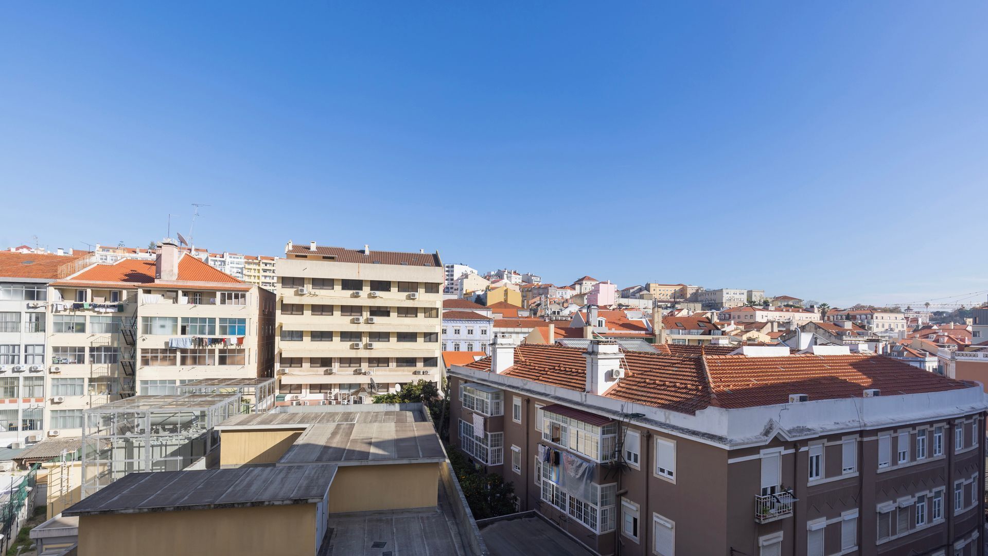 A high-rise building with multiple balconies and a clear view of the surrounding cityscape.