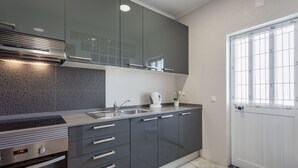 Une cuisine moderne avec des meubles gris, un évier en acier inoxydable et une bouilloire posée sur le plan de travail.