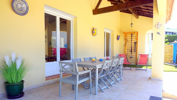 Una terrazza all'aperto con tavolo e sedie, una pianta in vaso e una scala di legno.