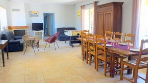 Un soggiorno con divano, televisione e zona pranzo con tavolo e sedie.