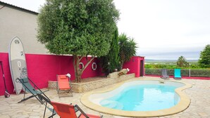 Area piscina con sedie a sdraio, una tavola da surf e vista sul paesaggio.