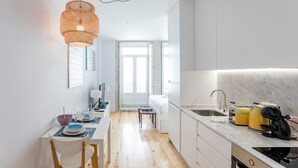 Una cocina moderna con armarios blancos, una mesa de comedor de madera y una lámpara colgante.