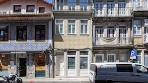 Una hilera de edificios con estilos arquitectónicos diferentes, incluyendo una tienda con fachada de azulejos y un cartel de estacionamiento.