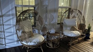 A room with two wicker chairs with cushions, a small round table, and a potted plant. - Family Fun only steps away from Saint Joe Beach! Gulf Views!! Swim Spa 15ftx7ft! (Port St. Joe)
