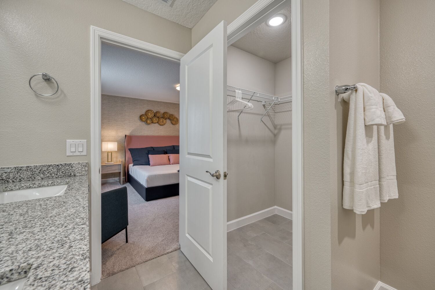 A bathroom with a granite countertop, a shower, and a towel rack.