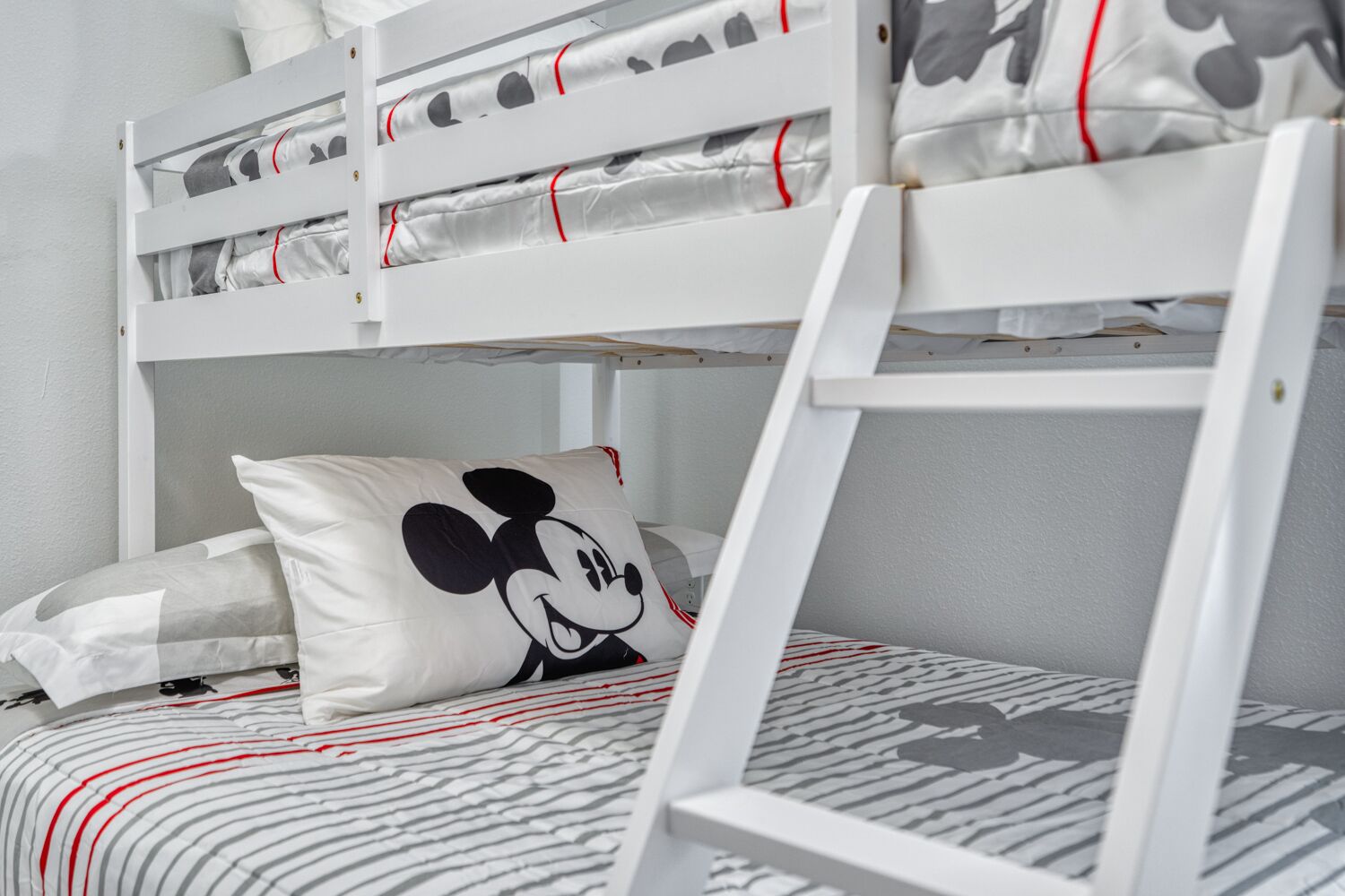 A bunk bed with a Mickey Mouse pillow and striped bedding.