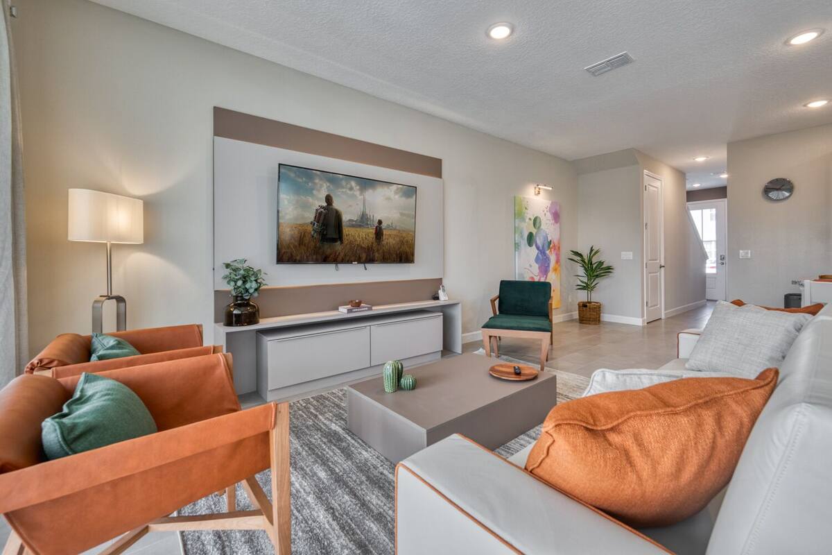 A modern living room with a sofa set, a coffee table, a TV mounted on the wall, and a painting above the sofa.