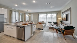 Una cocina moderna con una isla central, electrodomésticos integrados y un área de comedor con sofá y sillas.