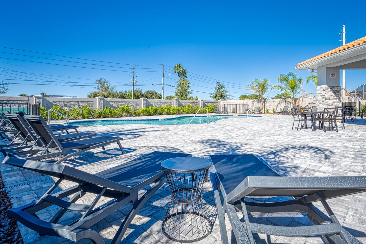 A pool area with lounge chairs, a table, and a stone patio.