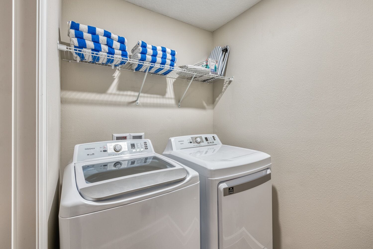 A laundry area with two front-loading washing machines and a drying rack with folded towels.