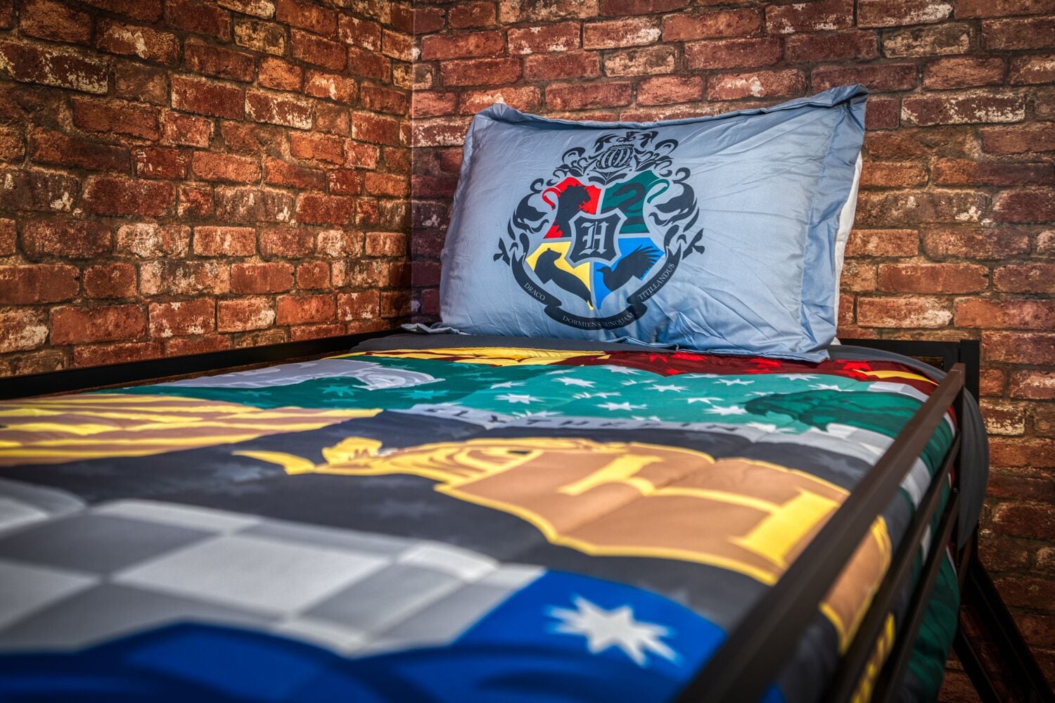 Ein Bett mit einer farbenfrohen Steude und einem Kissen mit Wappen.
