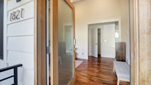 Un couloir doté d’un plancher en bois, d’un banc et d’une porte donnant sur une autre pièce.