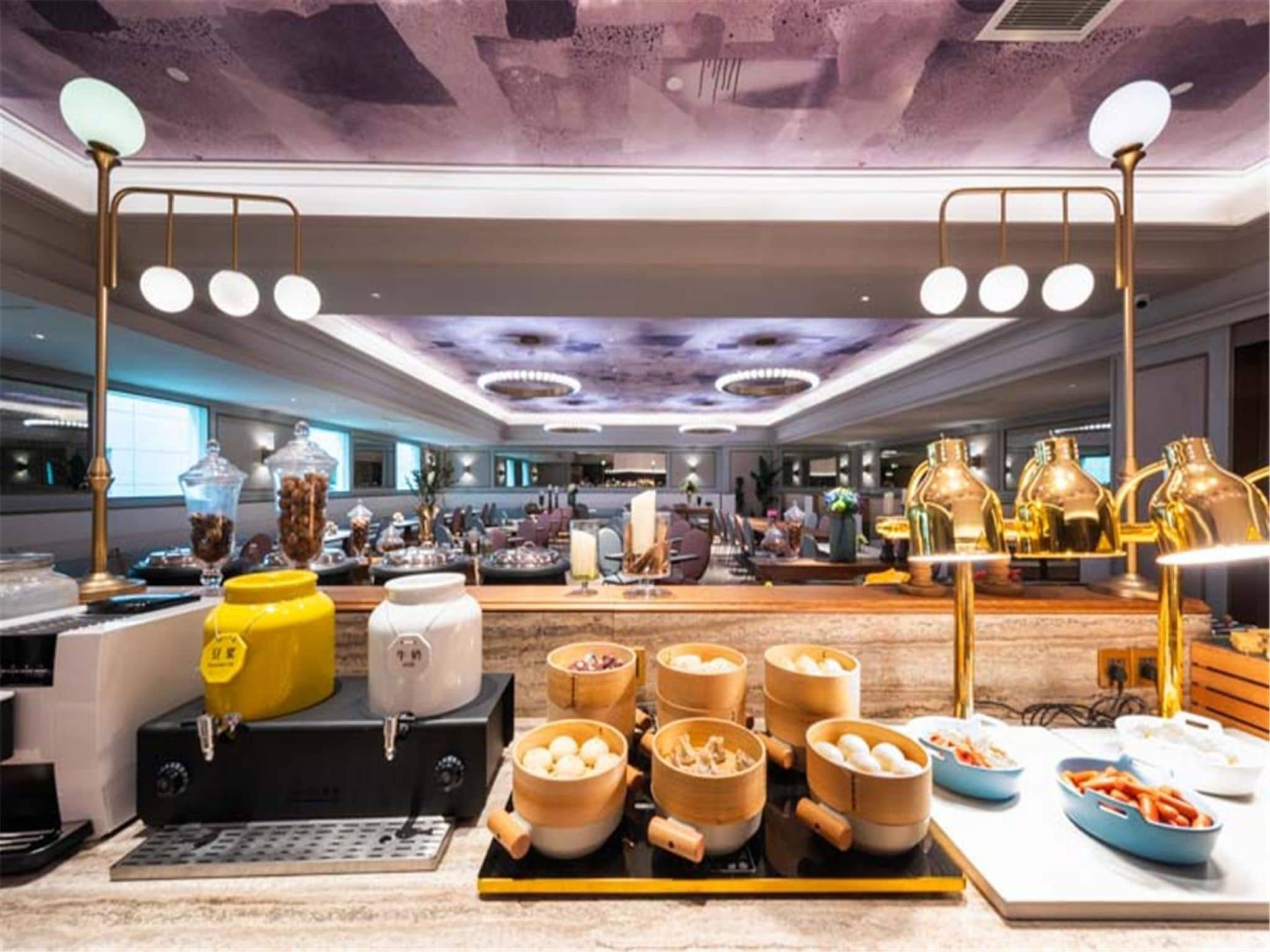 Um saguão de hotel com serviço de buffet, incluindo recipientes de comida e uma máquina de café.