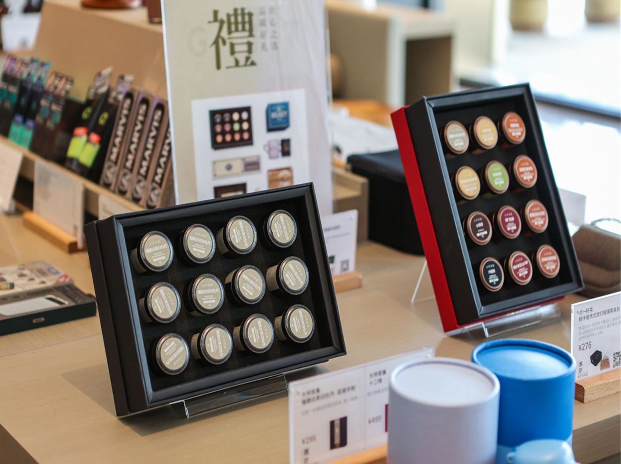 Two display cases with small jars, possibly containing samples or products, on a table with price tags.