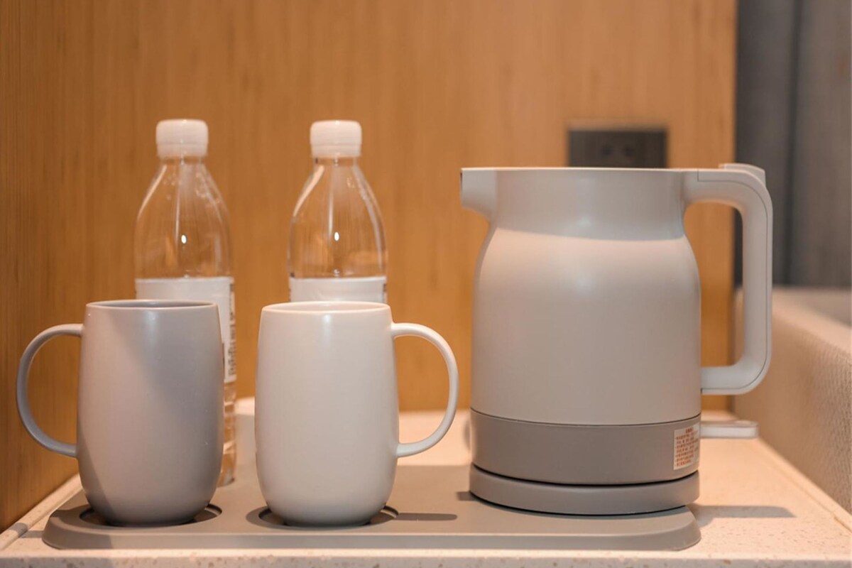 Una zona de kitchenette con una cafetera, dos tazas y dos botellas de agua.