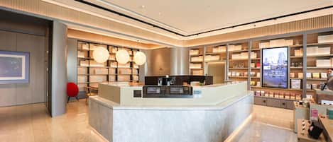 A modern hotel lobby with a reception desk, seating area, and book-lined shelves.