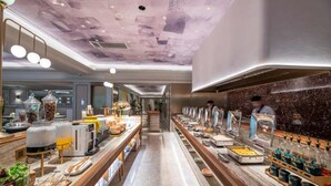 A buffet area with multiple food stations, a long counter, and a person in the background.