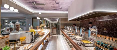 A buffet area with multiple food stations, a long counter, and a person in the background.