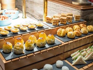 Un bufé con diversas opciones de comida, incluyendo pasteles, sándwiches y postres.