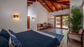 Un dormitorio con una cama grande, un escritorio y una silla, vigas de madera en el techo y vistas al exterior.