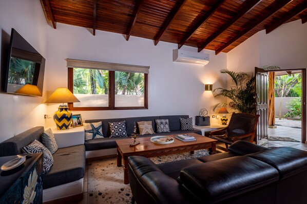 Una sala de estar con techo de madera, un juego de sofá, una mesa de centro y vistas al exterior.