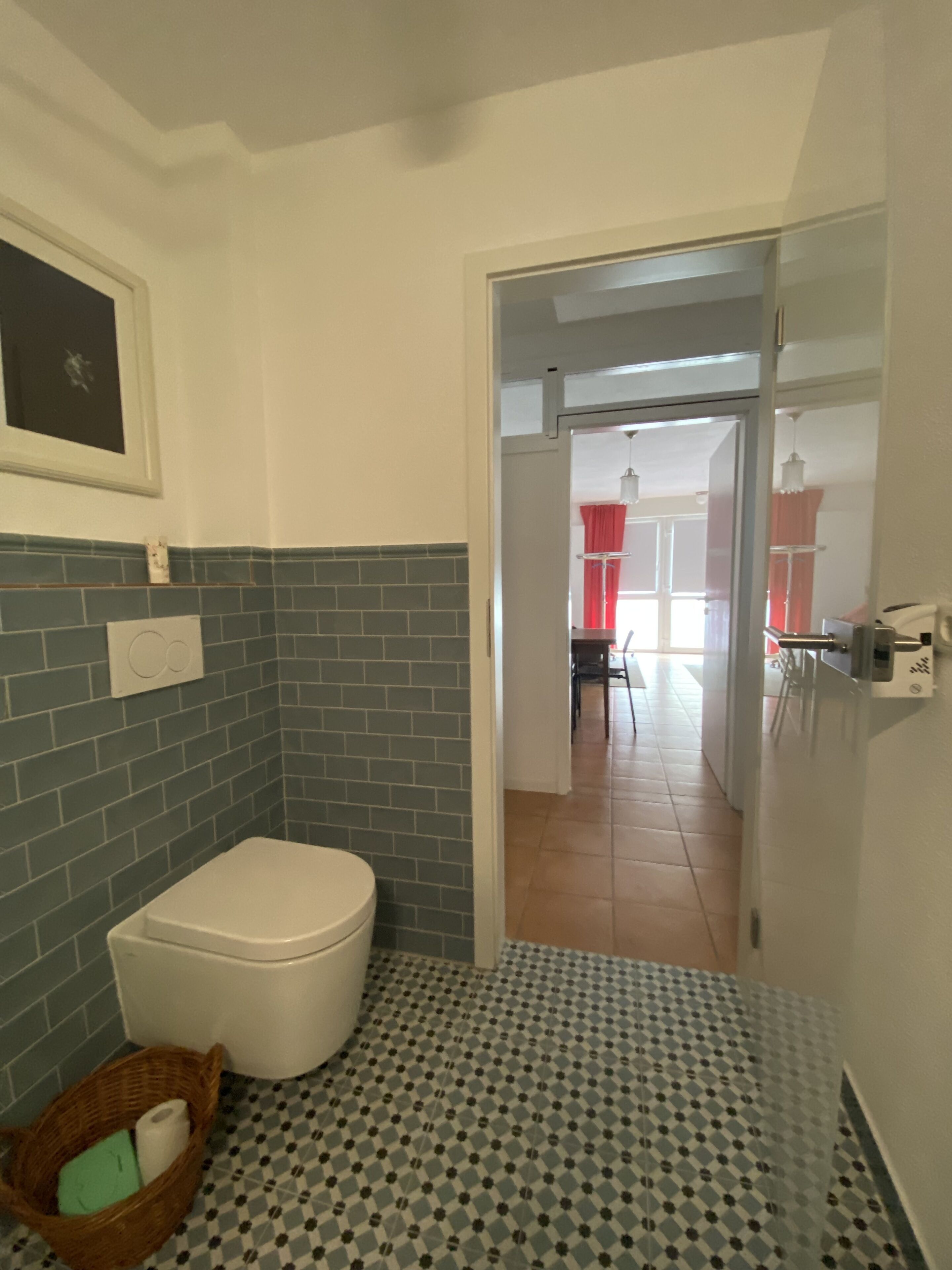 A bathroom with a toilet, a wicker basket with toiletries, and a patterned floor.