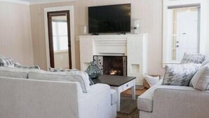 Una sala de estar con dos sofás, un televisor y una chimenea.
