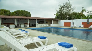 A pool area with white lounge chairs and blue towels, a covered seating area, and a bar. - Hotel RC Tonsupa (Tonsupa)