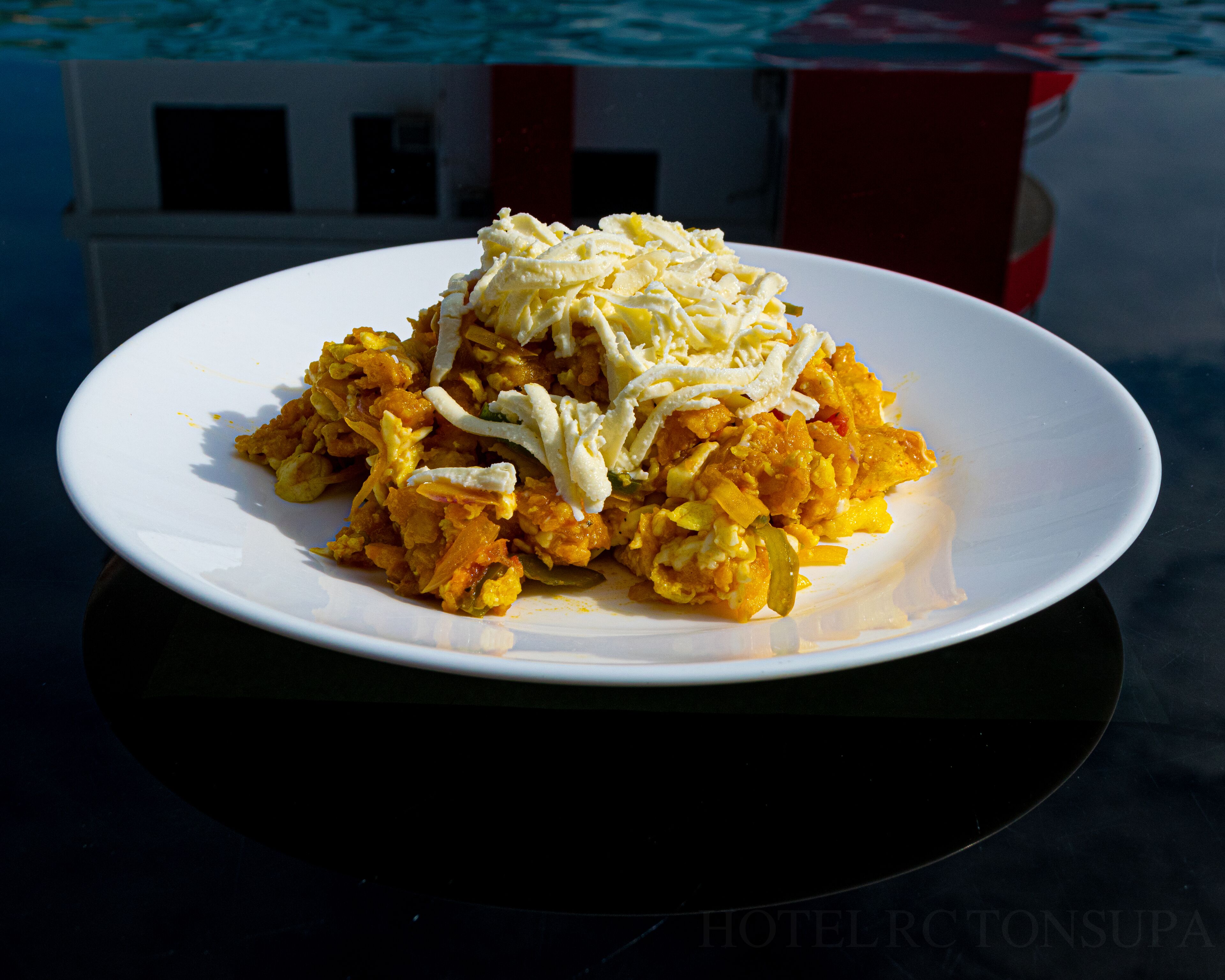 Un plato de huevos revueltos con queso sobre un plato blanco.