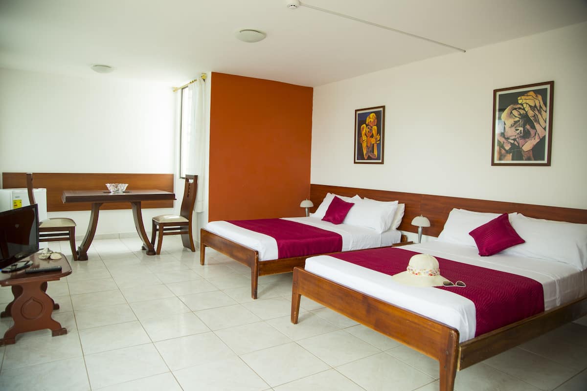 Quarto de hotel com duas camas, uma mesa e uma cadeira.