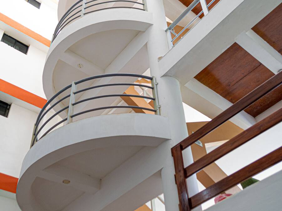 Un interior de varios niveles con una escalera en espiral, paredes blancas y detalles de madera.