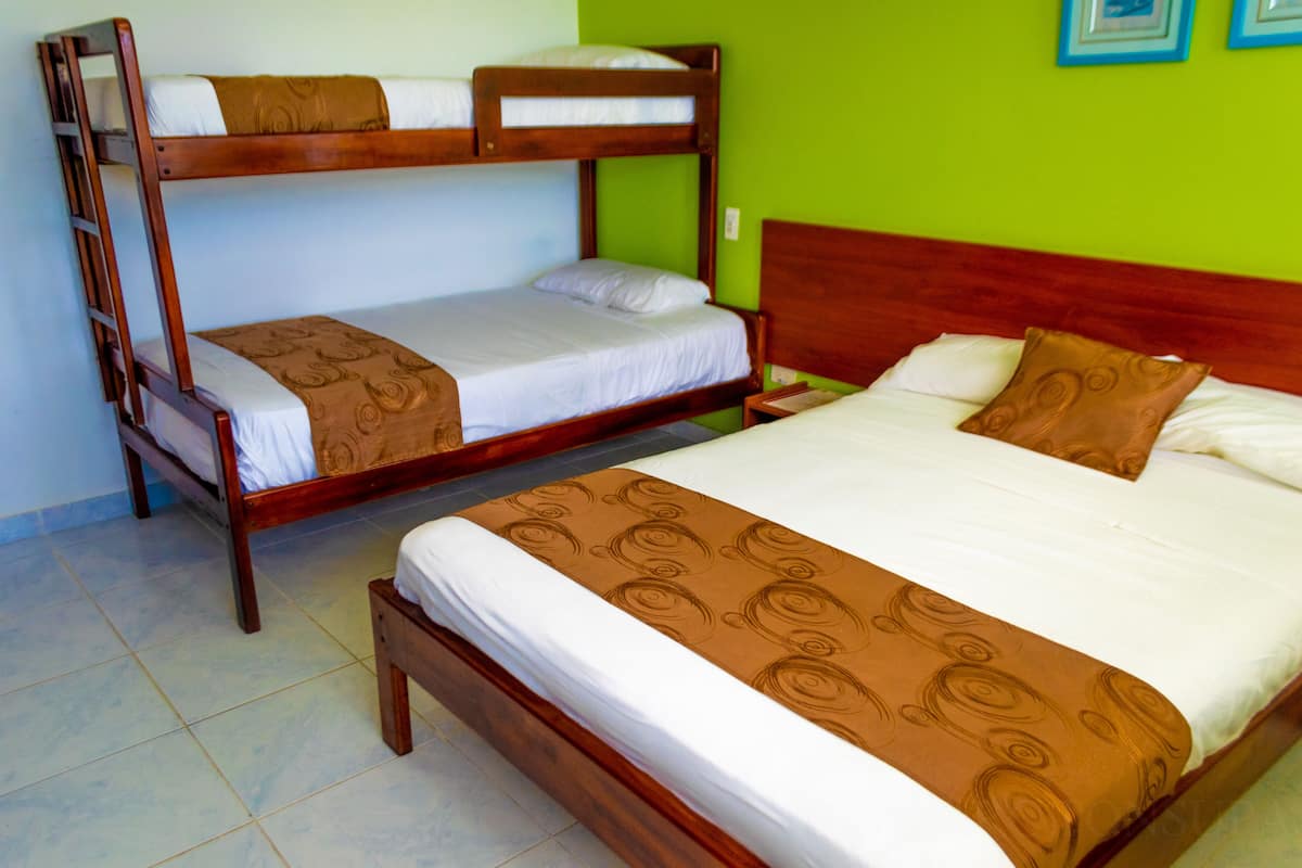 Quarto com duas beliches, cabeceira de madeira e parede verde.