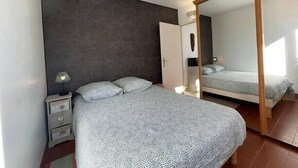 A bedroom with a bed, a nightstand, a mirror, and a wardrobe.