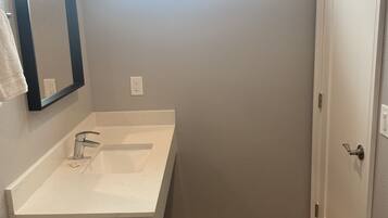 Un baño con un lavamanos blanco, un espejo y una puerta.