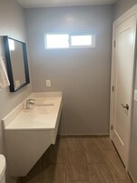 Un baño con un lavamanos blanco, un espejo y una puerta.