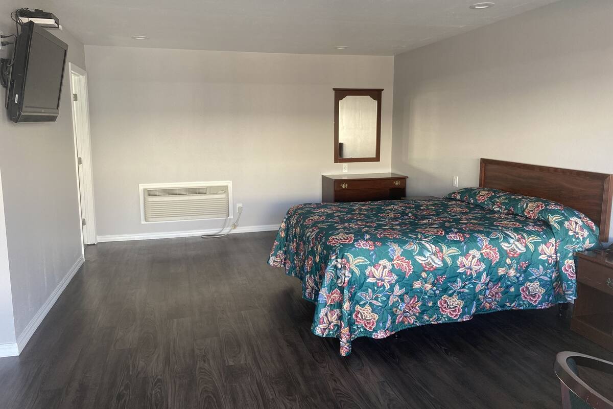 A bedroom with a wooden bed, a dresser, a mirror, and a ceiling fan.