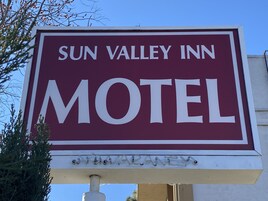 A sign for Sun Valley Inn Motel with a maroon background and white lettering.