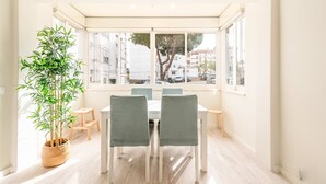 A bright dining area with a large window, a bamboo plant, and a table with chairs. - GuestReady - Great 3BDR apartment in Oeiras! (Oeiras)