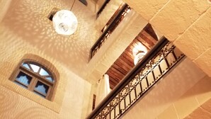 A multi-level interior with a wooden ceiling, a balcony with wrought iron railings, and hanging light fixtures.