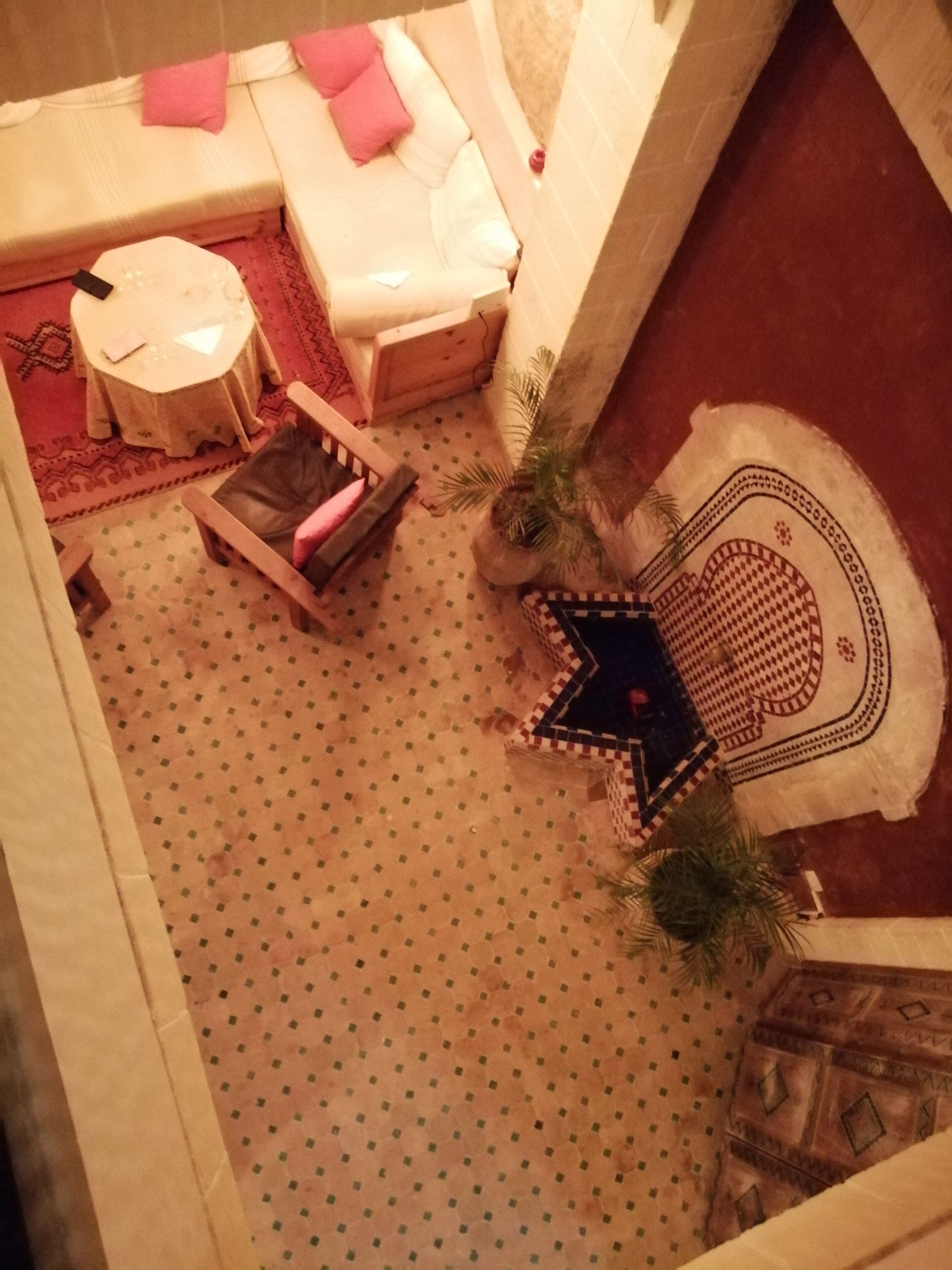 Una habitación con cama, una mesita, una silla y suelo estampado.